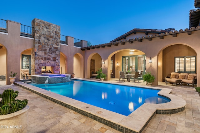 pool at dusk featuring an in ground hot tub, an outdoor hangout area, and a patio area