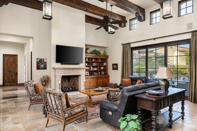 living room featuring ceiling fan, beamed ceiling, and a high ceiling