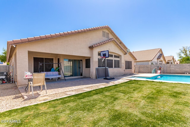 rear view of property featuring a patio area, a fenced in pool, and a yard