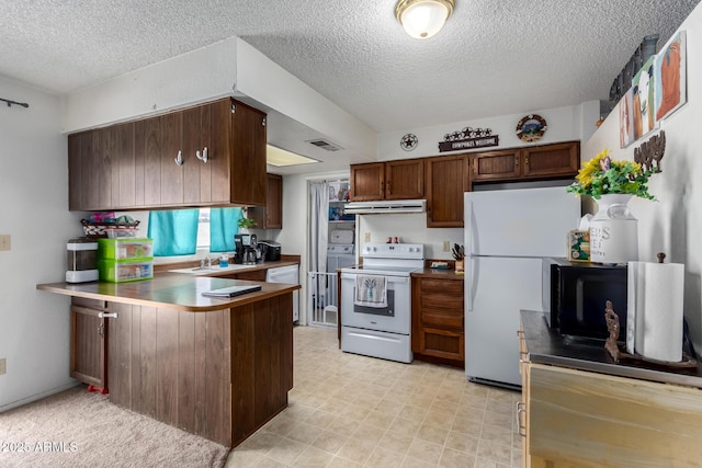 kitchen featuring white appliances, visible vents, a peninsula, light countertops, and under cabinet range hood