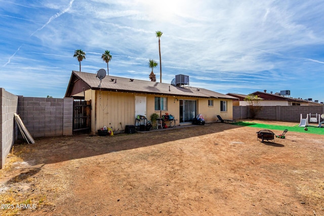 rear view of property with an outdoor fire pit and a fenced backyard