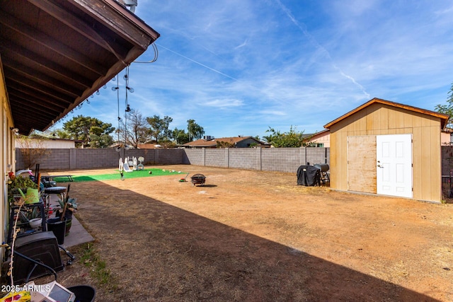 view of yard featuring an outbuilding, a shed, an outdoor fire pit, and a fenced backyard