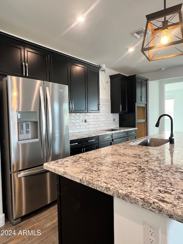 kitchen with sink, stainless steel fridge, decorative light fixtures, decorative backsplash, and hardwood / wood-style flooring