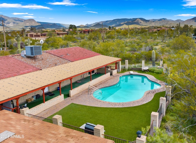 view of swimming pool featuring a patio, a mountain view, central AC unit, and a lawn