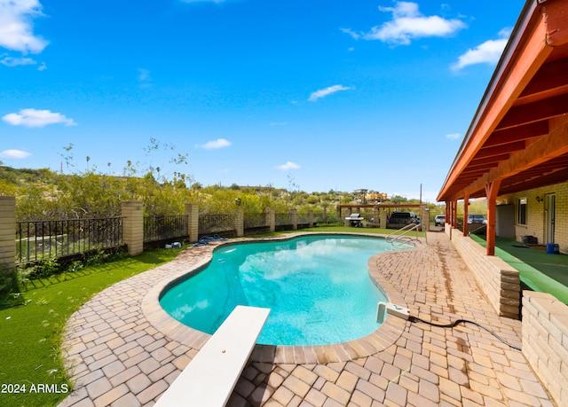 view of pool with a diving board and a patio area