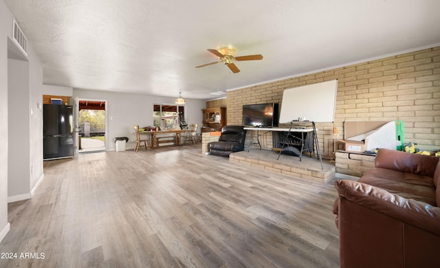 living room featuring ceiling fan, brick wall, and hardwood / wood-style floors