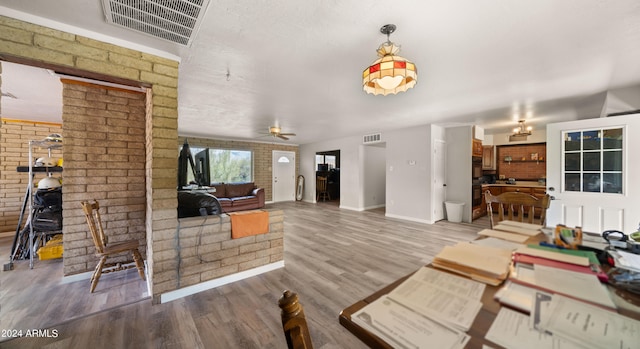 living room featuring ceiling fan, hardwood / wood-style flooring, and brick wall