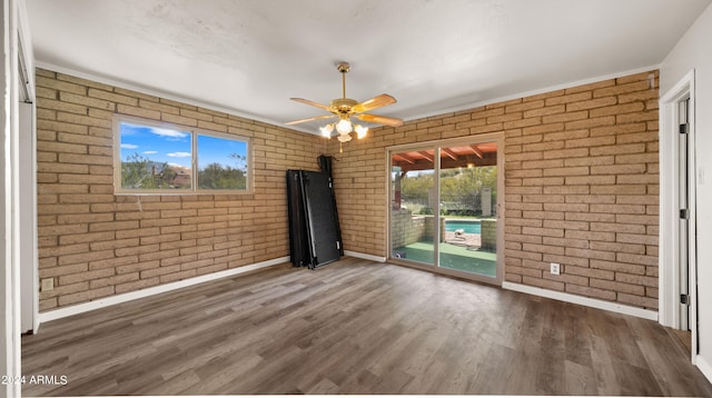 empty room with ceiling fan, brick wall, and dark hardwood / wood-style floors