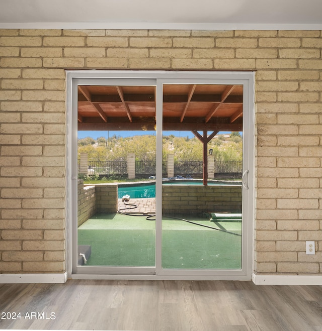 entryway featuring hardwood / wood-style flooring and brick wall