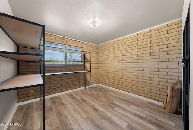 interior space featuring brick wall, hardwood / wood-style floors, and a textured ceiling