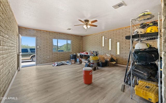 interior space featuring brick wall, a textured ceiling, hardwood / wood-style flooring, and ceiling fan