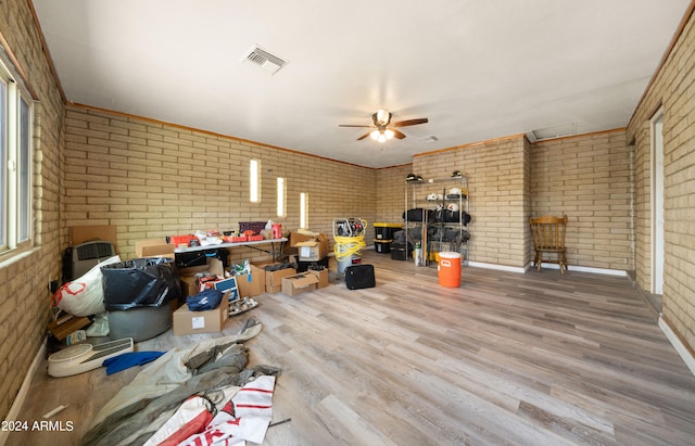 miscellaneous room with wood-type flooring, brick wall, and plenty of natural light