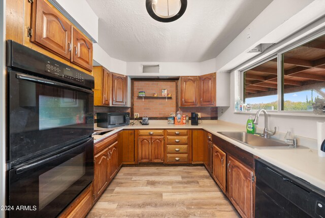 kitchen featuring decorative backsplash, sink, black appliances, a textured ceiling, and light hardwood / wood-style floors