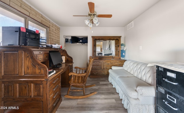 interior space featuring dark wood-type flooring, ceiling fan, and brick wall