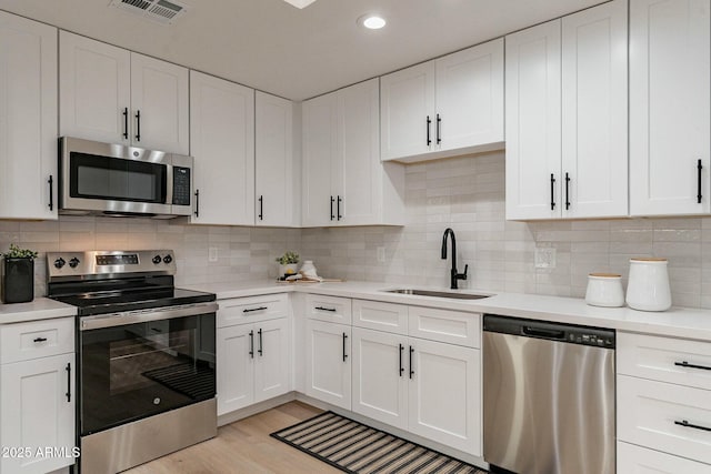 kitchen with stainless steel appliances, white cabinetry, and sink