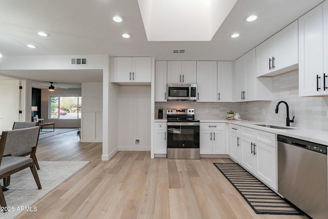 kitchen featuring appliances with stainless steel finishes, backsplash, ceiling fan, sink, and white cabinets