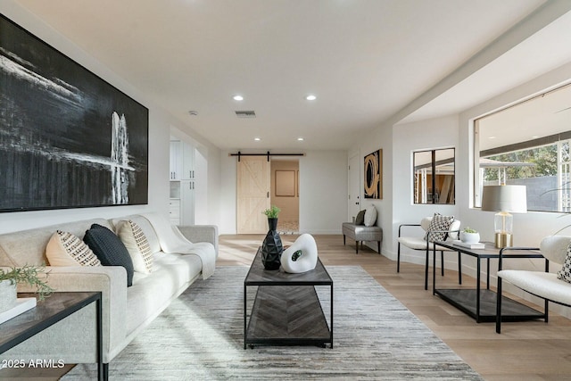 living room with a barn door and light hardwood / wood-style flooring