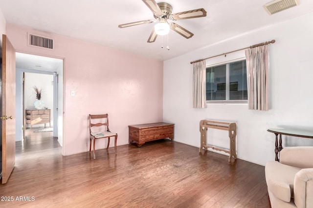 sitting room with a ceiling fan, wood finished floors, and visible vents