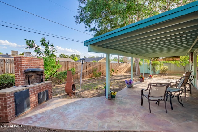 view of patio featuring a fenced backyard and an outdoor brick fireplace