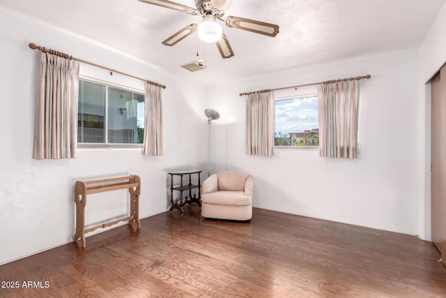 sitting room with ceiling fan, wood finished floors, and visible vents