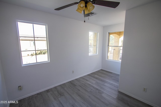 spare room featuring hardwood / wood-style floors, a wealth of natural light, and ceiling fan