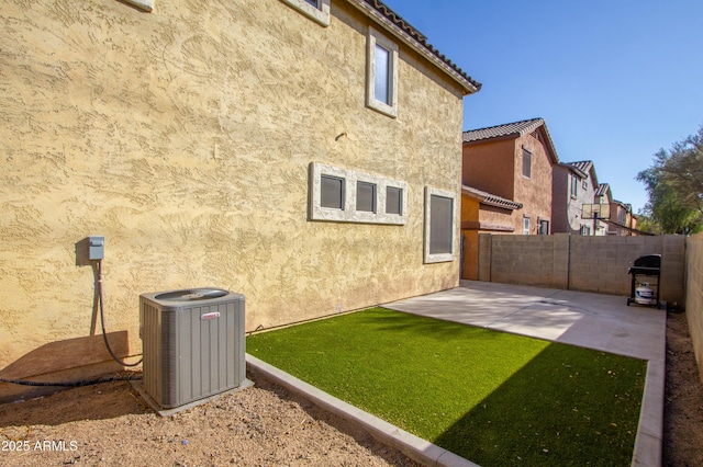 back of property with central AC unit, a lawn, and a patio