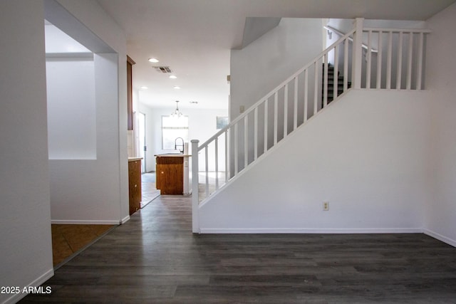 stairway featuring sink, hardwood / wood-style floors, and an inviting chandelier