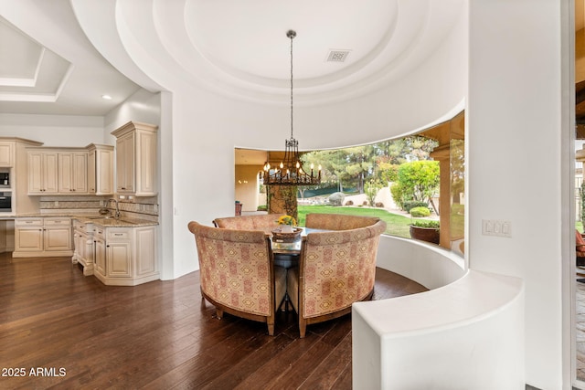 dining area featuring a tray ceiling, recessed lighting, visible vents, dark wood-type flooring, and a chandelier