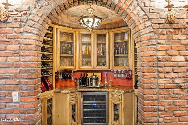 interior space featuring a dry bar, brick wall, wine cooler, brick ceiling, and a chandelier
