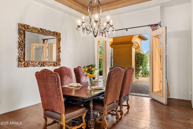 dining room featuring wood-type flooring, a healthy amount of sunlight, and an inviting chandelier