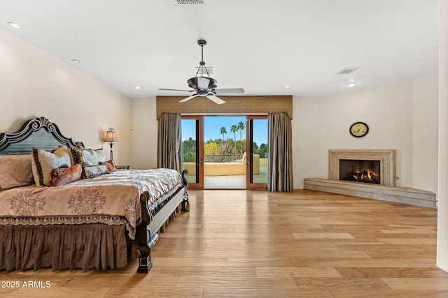 bedroom featuring light wood finished floors, access to outside, visible vents, and a high end fireplace