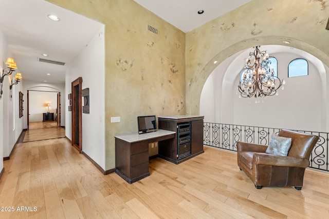 home office with light wood finished floors, visible vents, arched walkways, and baseboards