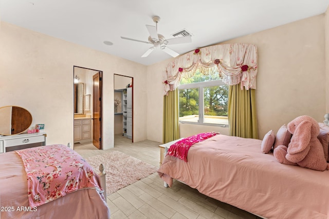 bedroom featuring ceiling fan, connected bathroom, visible vents, and light wood-style floors