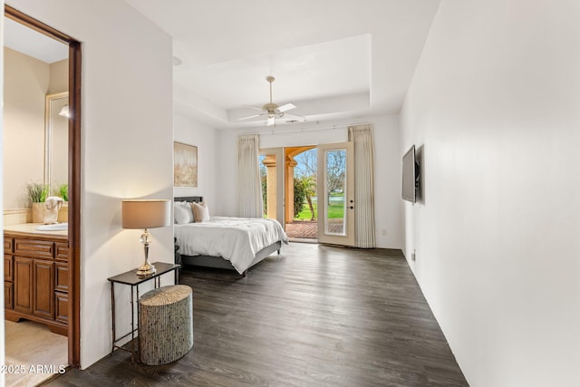 bedroom featuring ceiling fan, dark wood-style flooring, a raised ceiling, and access to exterior