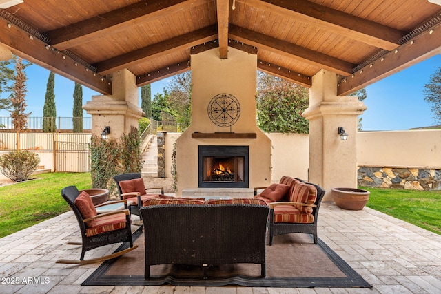 view of patio with an outdoor living space with a fireplace and fence