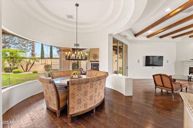 dining space with dark wood-type flooring, a warm lit fireplace, beam ceiling, and an inviting chandelier