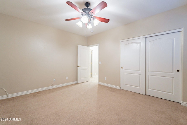 unfurnished bedroom featuring light carpet, a closet, and ceiling fan