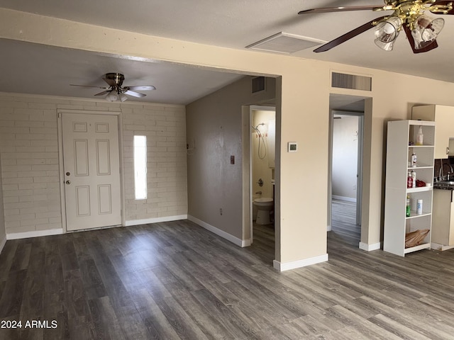 entrance foyer featuring dark hardwood / wood-style floors, ceiling fan, and brick wall