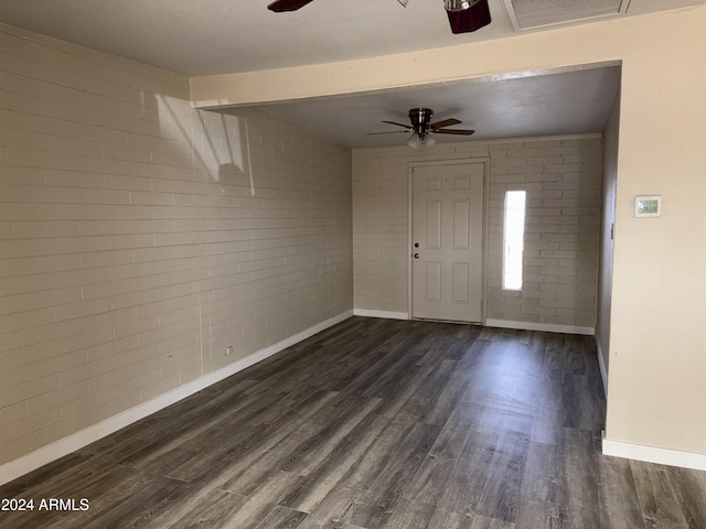 foyer entrance featuring beam ceiling, dark hardwood / wood-style floors, and brick wall