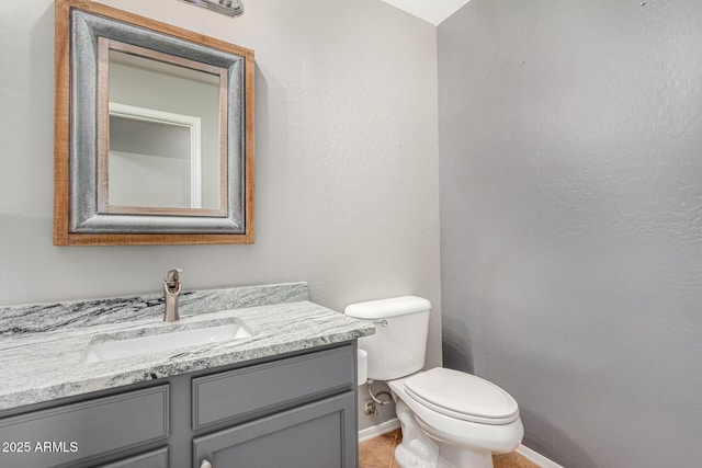 half bathroom featuring baseboards, vanity, and toilet