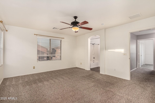 spare room featuring visible vents, dark carpet, and a ceiling fan