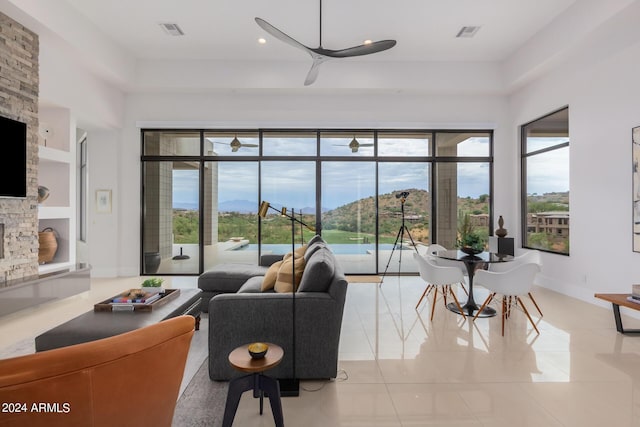 living area featuring visible vents, a stone fireplace, ceiling fan, and light tile patterned flooring