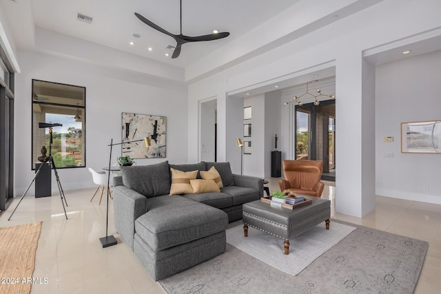 living room featuring a raised ceiling, light tile patterned floors, a ceiling fan, and visible vents