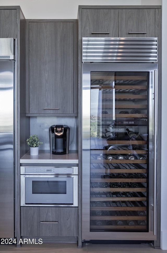 kitchen with wine cooler, appliances with stainless steel finishes, modern cabinets, and light countertops