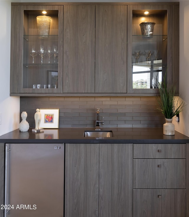 bar with decorative backsplash, freestanding refrigerator, and a sink