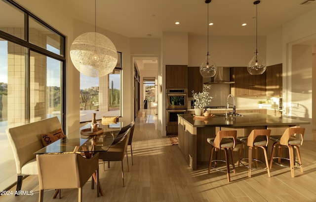 kitchen featuring light wood-type flooring, modern cabinets, a spacious island, dark countertops, and wall chimney range hood