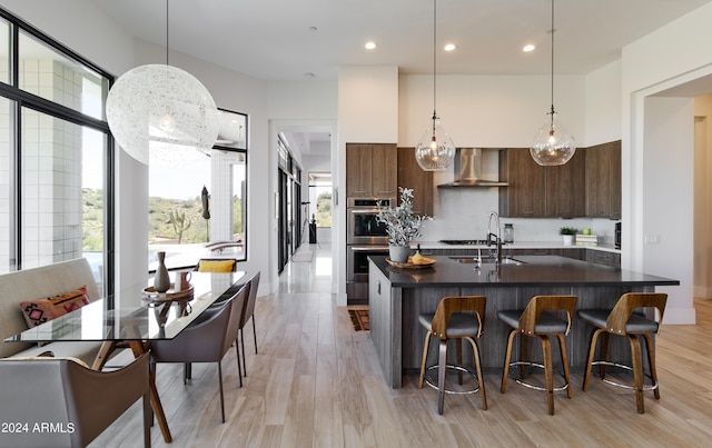 kitchen featuring double oven, dark countertops, wall chimney exhaust hood, and modern cabinets