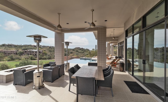 view of patio / terrace featuring outdoor dining space, a ceiling fan, an outdoor pool, and an outdoor fire pit