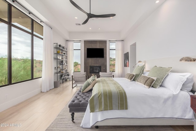 bedroom featuring recessed lighting, a large fireplace, baseboards, and wood finished floors