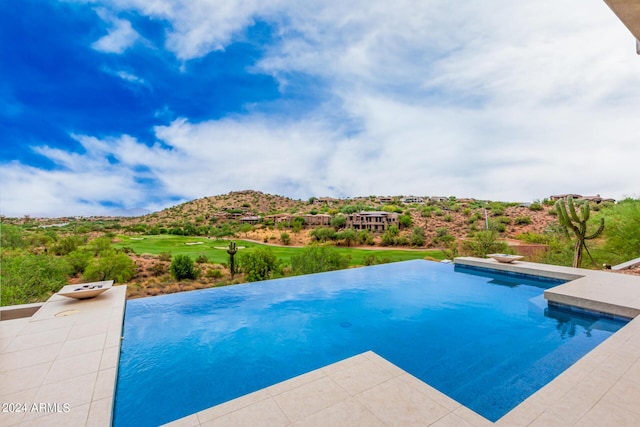 view of swimming pool with a mountain view and an infinity pool